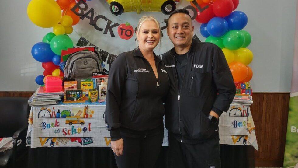 two people in front of school supplies and balloons